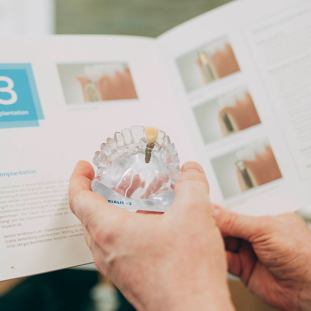 Patientin liest sich Broschüre zu Zahnimplantaten aus Laupheim durch.