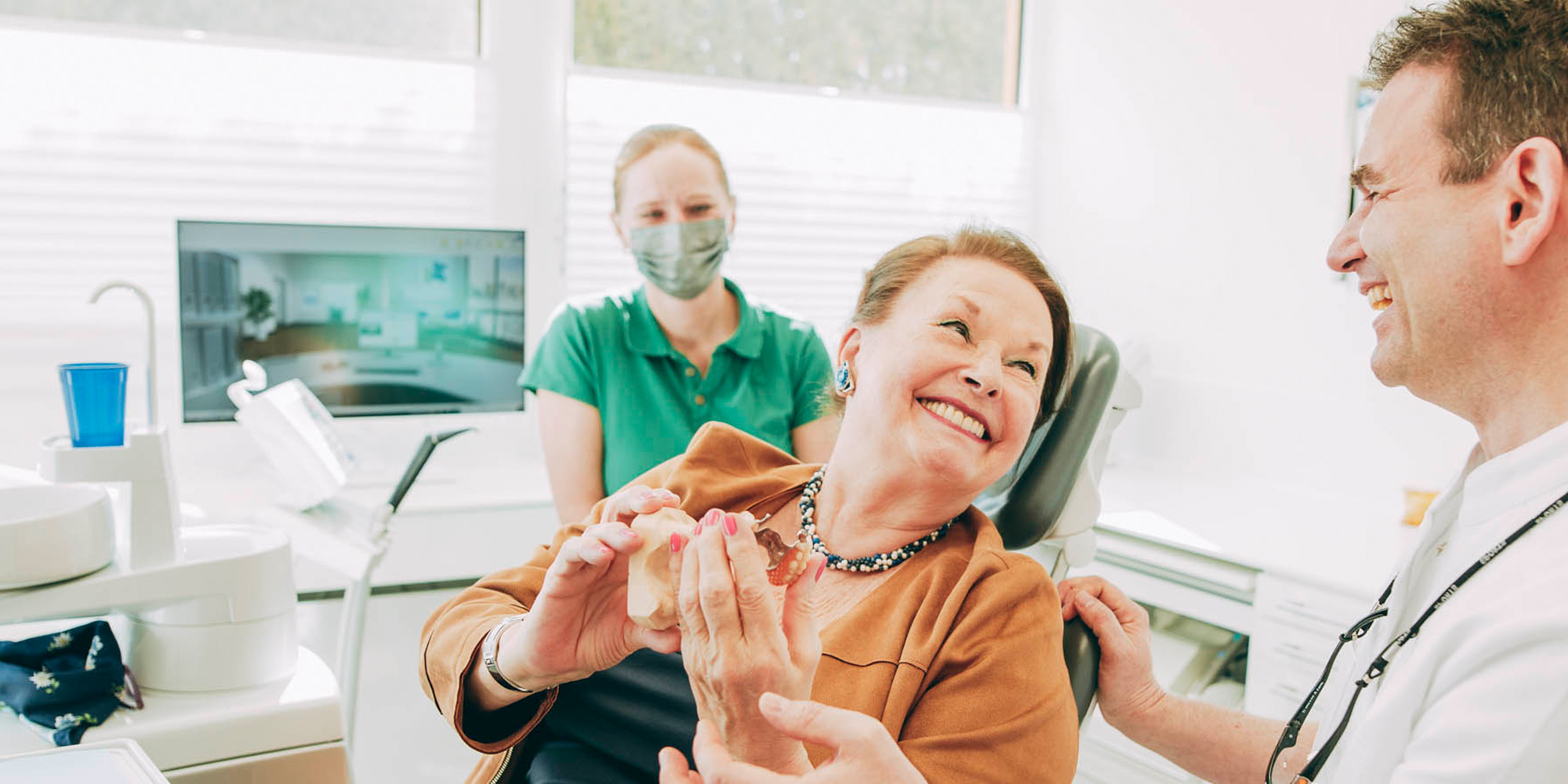 Patientin freut sich über sicheren Biss mit Zahnimplantaten aus Laupheim.