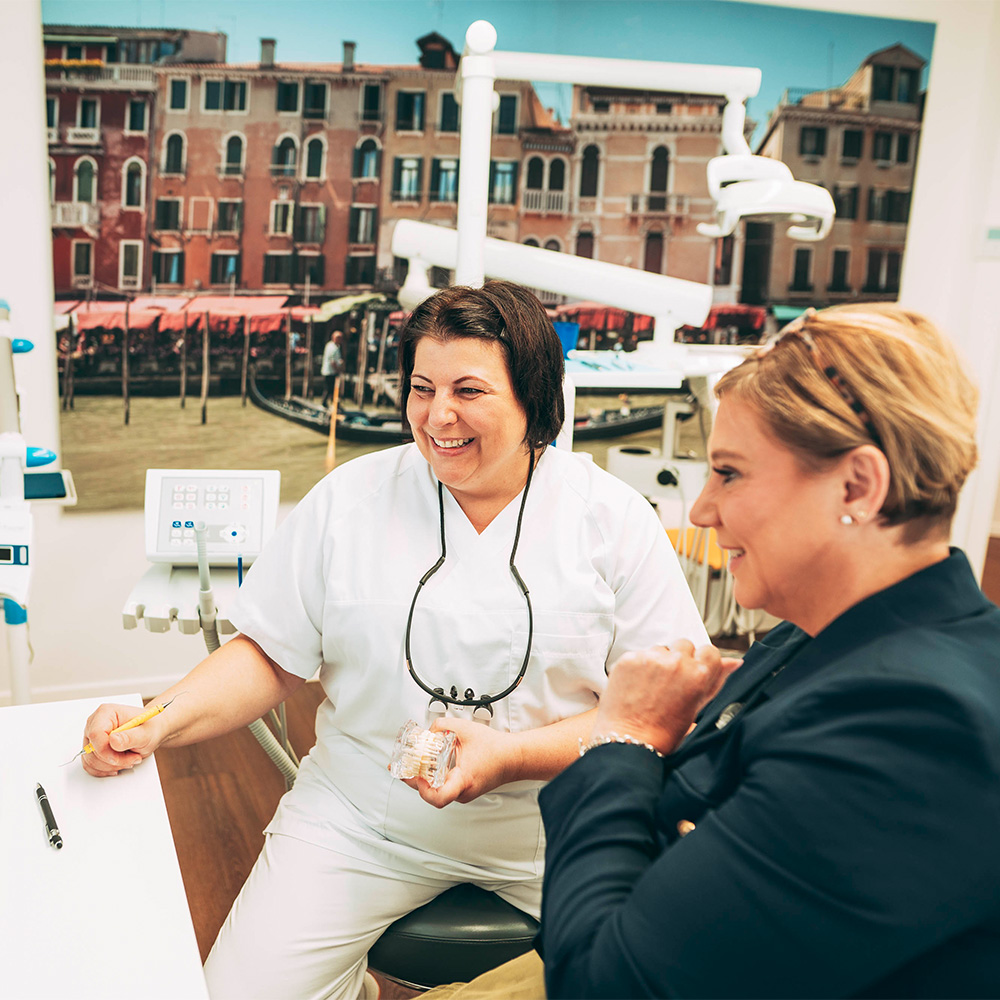 Zahnarzt spricht mit Patientin über Parodontosebehandlung Laupheim.