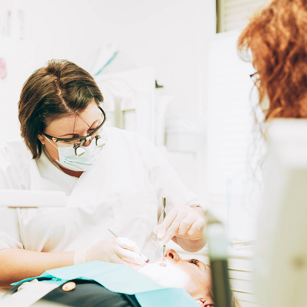 Zahnärztin reinigt die Zähne – das gehört zur Parodontosebehandlung Laupheim.