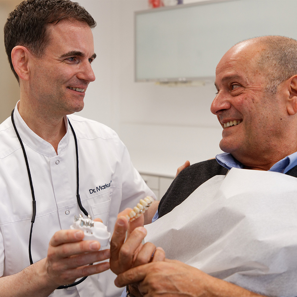 Dr. Traub klärt Patient über passenden zahnersatz auf.