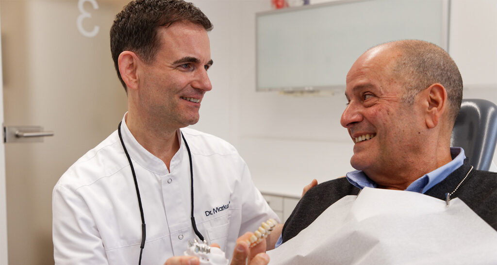 Senior lacht mit Brücken und Zahnprothesen aus Laupheim glücklich und zufrieden.